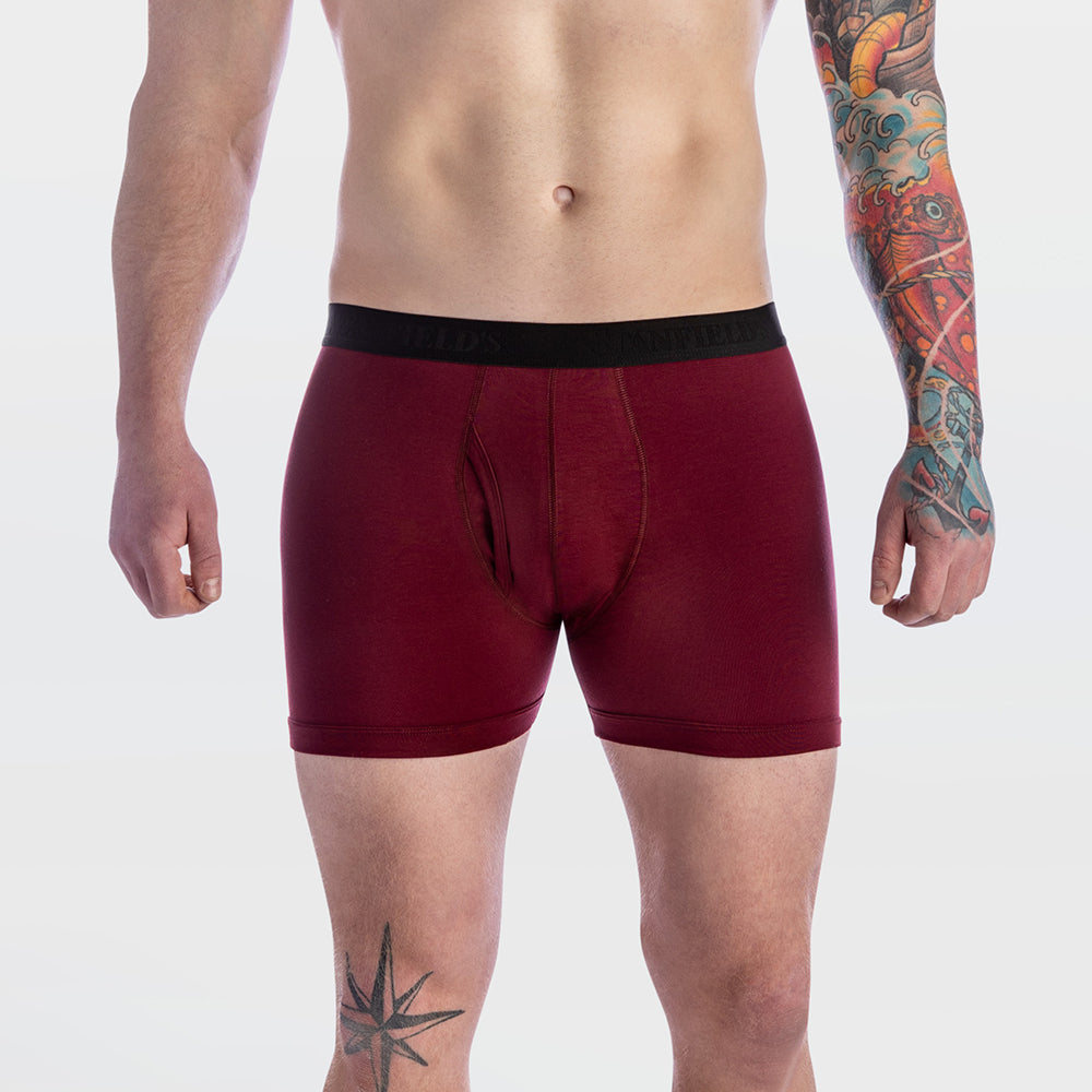 Maroon boxer briefs worn by a person with tattoos on a light gray background