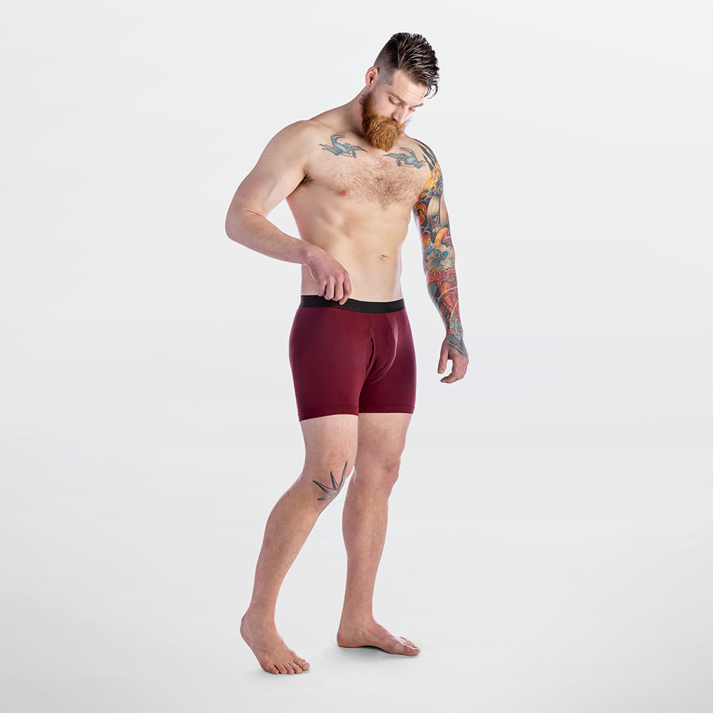 Man wearing maroon boxer briefs on a white background